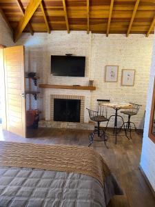 a bedroom with a fireplace with a television and a table at Chale Villa do Valle in Monte Verde
