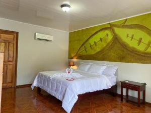 a bedroom with a white bed with a painting on the wall at Hotel & Hot Springs Sueño Dorado in Fortuna