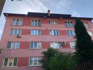 萨拉热窝SH Apartments Bistrik-Sarajevo的一栋有窗户和树的高大的红色建筑