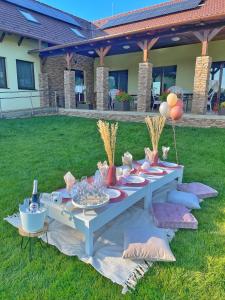 una mesa de picnic en la hierba con comida y globos en Auróra Rendezvényterem & Szállás, en Jászapáti