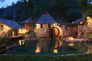 a pond in front of a stone house at night at Rafting Camp Tara Center Tri Vodenice in Bastasi