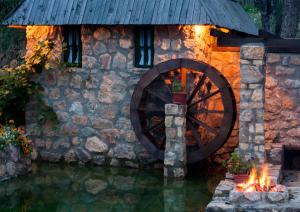 a wooden water wheel in front of a stone building at Rafting Camp Tara Center Tri Vodenice in Bastasi