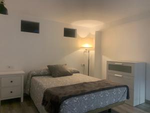 a small bedroom with a bed and a night stand at HOLIDAY ALYMA in Sanlúcar de Barrameda