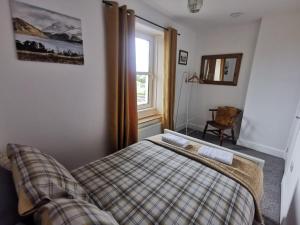 a bedroom with a plaid bed and a window at Welcoming 2 bedroom home with large outdoor space in Aspatria
