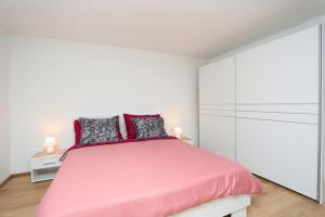 een witte slaapkamer met een roze bed en witte kasten bij Holiday house Nono in Labin