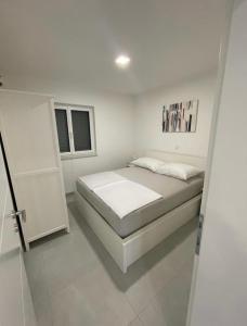 - une chambre blanche avec un lit et une fenêtre dans l'établissement Luxury Apartment SWANY, à Crikvenica