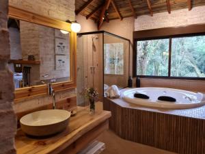 uma grande casa de banho com uma grande banheira e um lavatório em Pousada Toca Da Coruja em Monte Verde