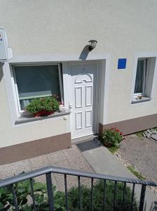 une porte blanche sur un bâtiment avec des fleurs dans une fenêtre dans l'établissement Apartment Zlatko, à Matulji