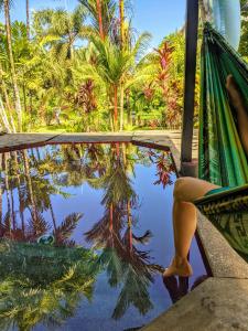 a person in a hammock next to a pool of water with palm trees at Pool house, Casa Luna in Pavones