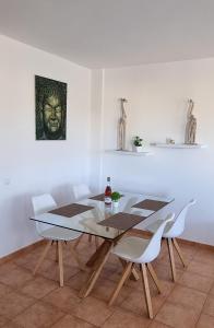 a dining room with a table and white chairs at Tres Islas Apartment - 70 m2 private terrace in Corralejo