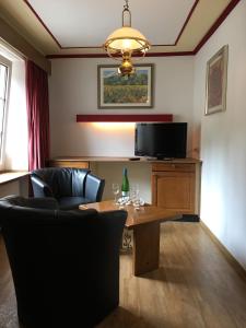 a living room with a table and chairs and a television at Bed & Breakfast du Château in Vianden