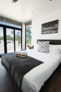 1 cama blanca grande en una habitación con ventanas en Hacienda Los Golfo, en Valle de Guadalupe