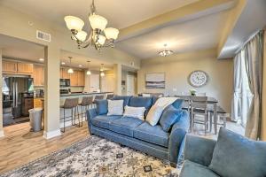 a living room with a blue couch and a kitchen at Grand Haven Condo - Walk to Nearby Hot Spots! in Grand Haven