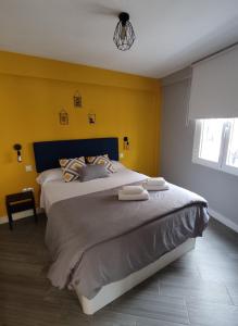een slaapkamer met een groot bed met gele muren bij The2G Beach Apartment in Torremolinos