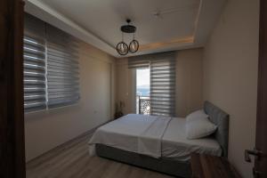 Schlafzimmer mit einem Bett und einem Fenster mit Aussicht in der Unterkunft BRAGEÇAM REZİDANS OTEL in Konak