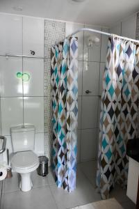 a bathroom with a toilet and a shower curtain at Pérola de Bombinhas in Bombinhas +59 photos