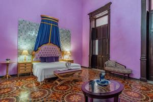 - une chambre avec des murs violets, un lit et une table dans l'établissement Hotel Lavanda CAS Merida, à Mérida