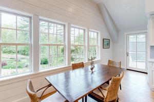 a dining room with a table and chairs and windows at Coveside Carriage House in Boothbay Harbor