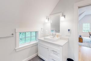 a white bathroom with a sink and a window at Coveside Carriage House in Boothbay Harbor