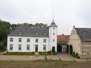 a large white building with a clock tower at Stately 16-person manor farm in South Limburg in Schimmert