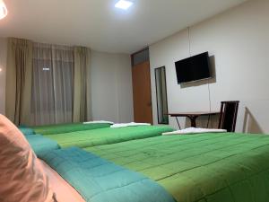 a room with four green beds with a flat screen tv at Hotel Herusalen in Arequipa