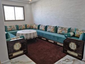 - un salon avec un canapé bleu et une table dans l'établissement Appartement bien situé Dahomey city . Bahia beach, à Bouznika