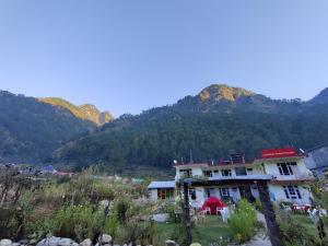 a house on a hill with mountains in the background at Breathe Inn in Kasol
