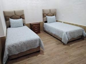 twee bedden in een kamer met houten vloeren bij Appartement bien situé Dahomey city . Bahia beach in Bouznika