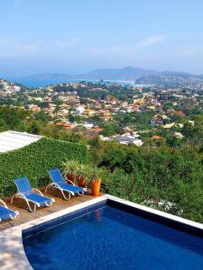 a swimming pool with chairs and a view of a city at O HOTEL in Búzios