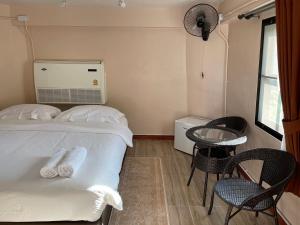 a bedroom with a bed and chairs and a window at Chaisuk Bungalow in Aranyaprathet