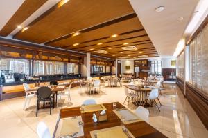 a restaurant with tables and chairs and windows at Grand Hotel Vientiane in Vientiane