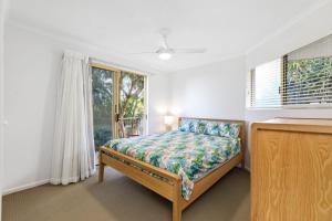1 dormitorio con cama y ventana en 6 Pacific Outlook Modern unit with lovely Ocean Views Pool in Complex Walk to Beach, en Sunshine Beach