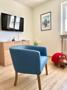 ein Wohnzimmer mit einem blauen Stuhl und einem TV in der Unterkunft Komfort Ferienwohnung nähe Bosenberg in Sankt Wendel