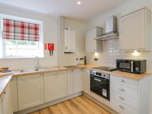 a kitchen with white cabinets and a microwave at North Firbank - Culzean Castle in Maybole