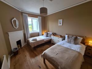 1 dormitorio con 2 camas y chimenea en South Lodge, Glenfintaig, en Spean Bridge