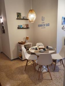 una mesa con sillas blancas en una habitación en Terra di Sud Rooms en Lecce