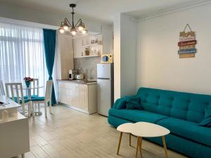 a living room with a blue couch and a kitchen at SUNSET MEMORIES ApartHotel Pool & Spa Mamaia Nord in Mamaia Nord