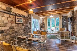 a living room with a stone wall and a table and chairs at Sakley's Cottages in Nainital