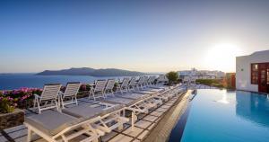 a row of chairs sitting on the edge of a swimming pool at Nikos Villas in Oia