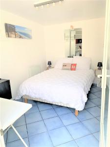 sypialnia z białym łóżkiem i niebieską podłogą wyłożoną kafelkami w obiekcie Chambre cosy indépendante dans jardin verdoyant. w mieście Le Bouscat