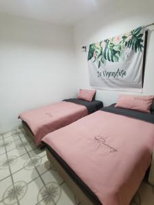 two beds in a room with pink sheets at Aim Houze in Udon Thani