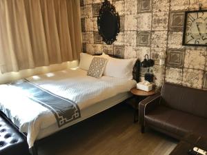 Cama en habitación con sofá y reloj en la pared en 台中一中街格雷熊, en Taichung