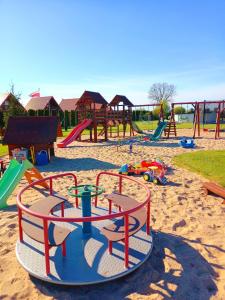 a playground with a bunch of play equipment in the sand at Domki Letniskowe Paula in Darłowo