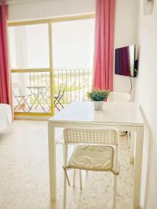 een witte tafel en stoel in een kamer met een raam bij ESTUDIO BLEGAMAR VISTAS - Playa, WiFi y Aparcamiento in El Puerto de Santa María
