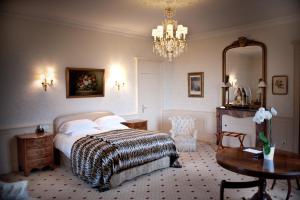 a hotel room with a bed, table, lamps and a mirror at Château D'Apigné Rennes in Le Rheu