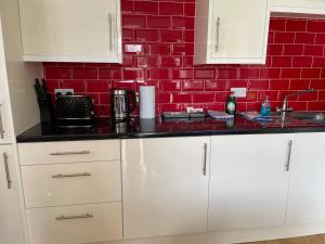 a kitchen with white cabinets and a red brick wall at Garden flat near the University of York in York