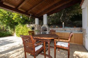 クルクにあるApartment PORTAPISANA just 50m from the beachのパティオにある木製のテーブルと椅子