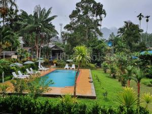 a swimming pool in a resort with chairs and trees at Malulee KhaoSok Resort in Khao Sok National Park