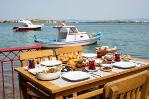a table with food and a boat in the water at Ferahi Evler Ayvalık in Ayvalık