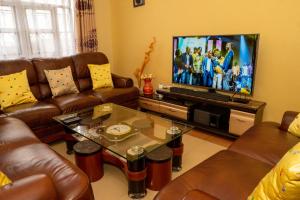 sala de estar con sofás de cuero y TV de pantalla plana en Bonaventure Apartment, en Kisumu